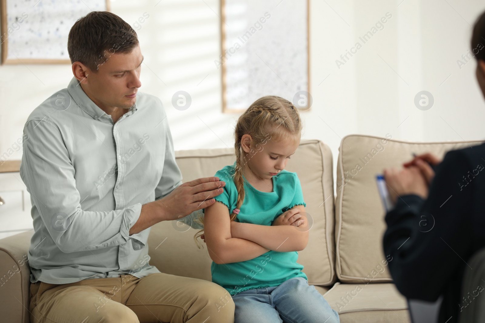 Photo of Little girl and her father on appointment with child psychotherapist indoors