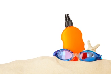 Photo of Bottle of sun protection body cream and diving goggles in sand against white background