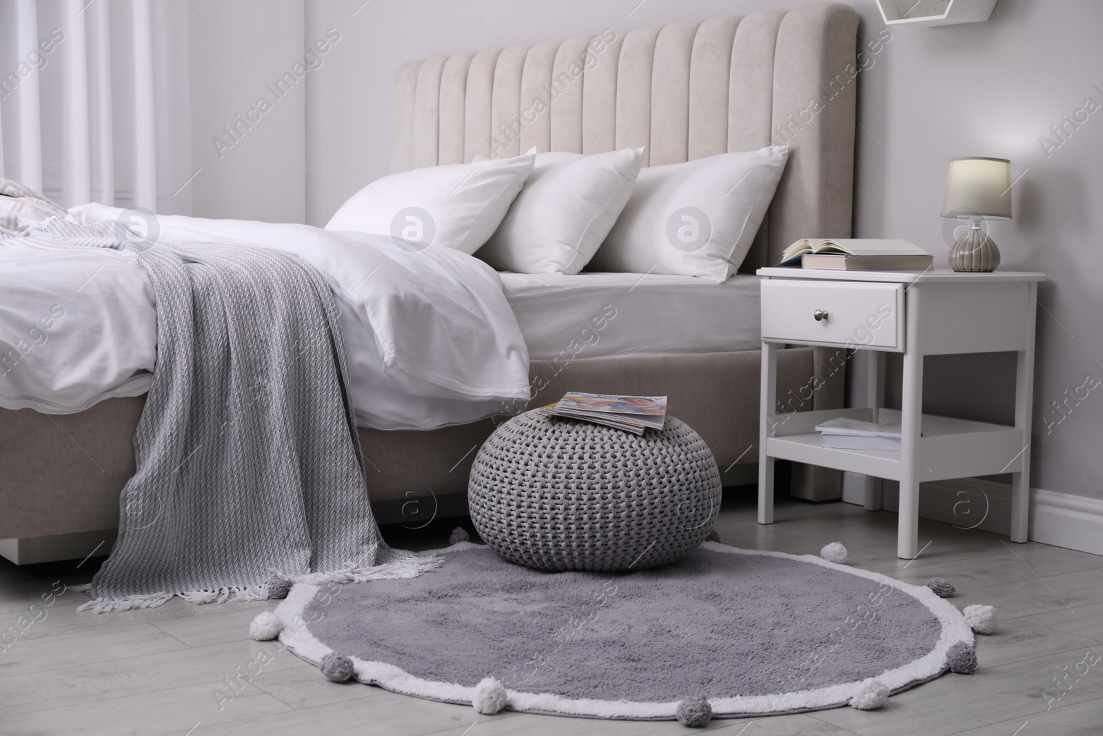 Photo of Stylish bedroom interior with knitted pouf and furniture