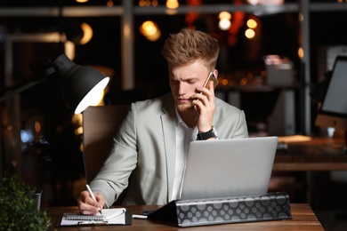 Photo of Young man working in office at night