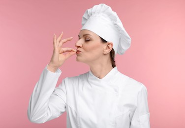 Photo of Happy woman chef in uniform showing perfect sign on pink background