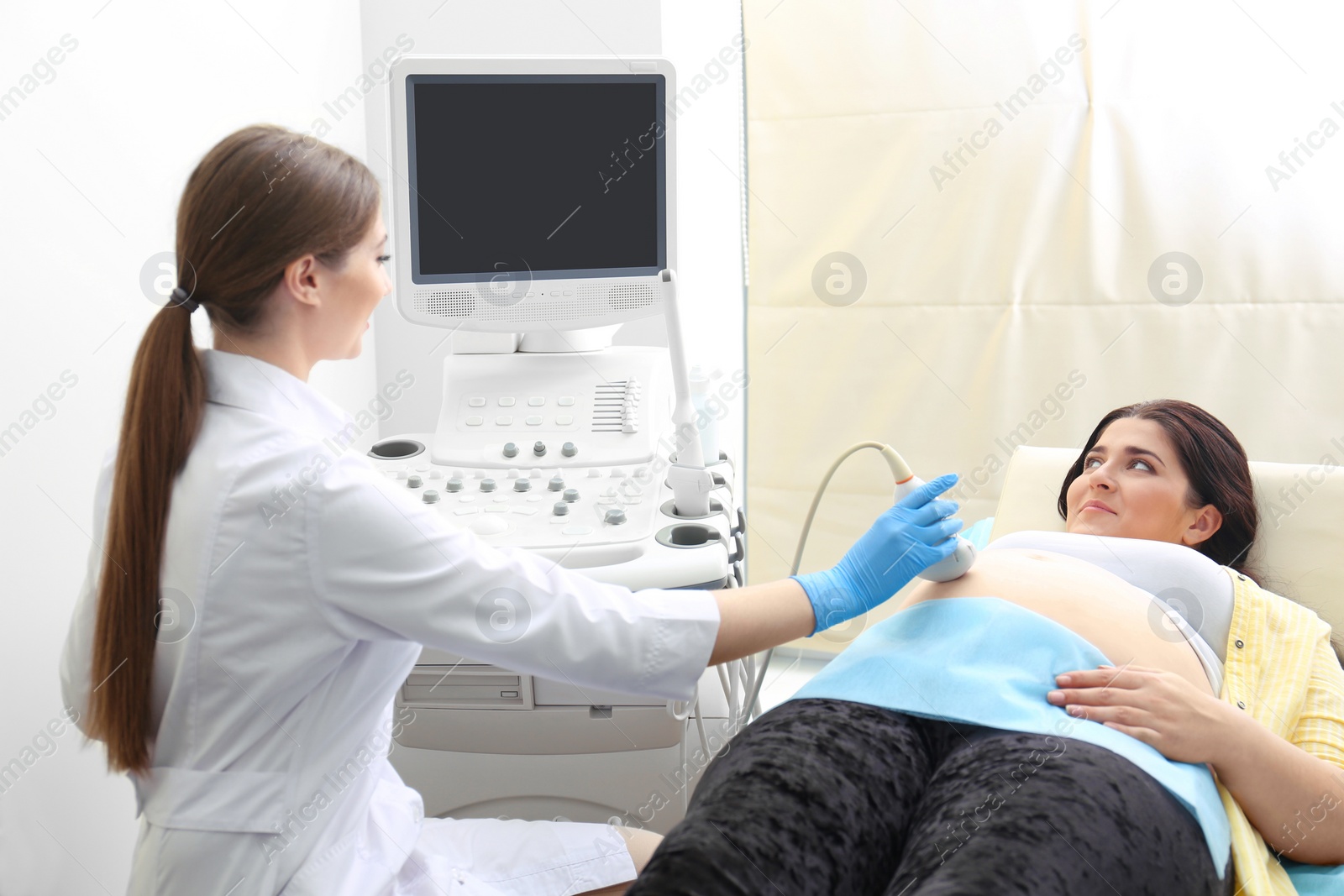 Photo of Young pregnant woman undergoing ultrasound scan in clinic