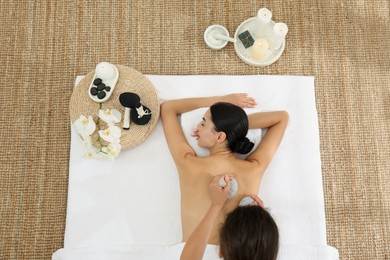 Photo of Young woman receiving herbal bag massage in spa salon, top view