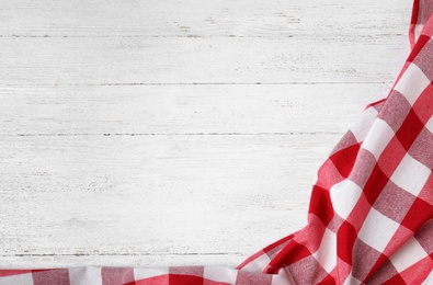 Photo of Checkered picnic blanket on wooden background, top view. Space for text