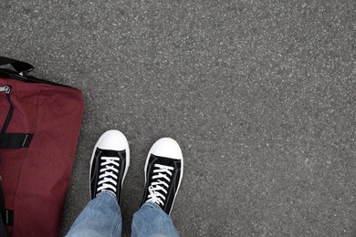 Photo of Man with bag standing on asphalt, top view. Space for text