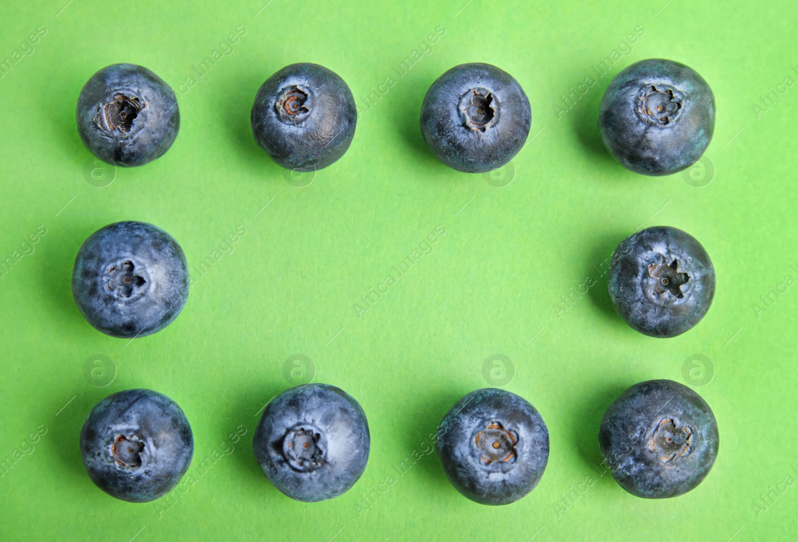 Photo of Frame of fresh ripe blueberries on green background, flat lay. Space for text