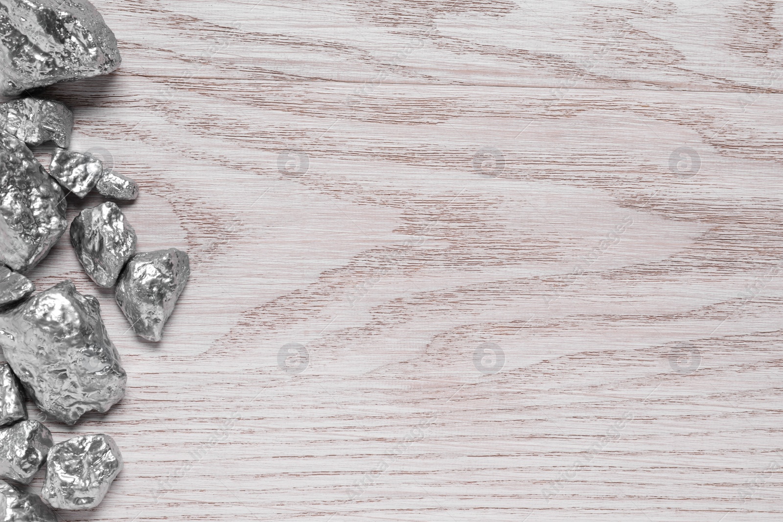 Photo of Pile of silver nuggets on white wooden table, flat lay. Space for text