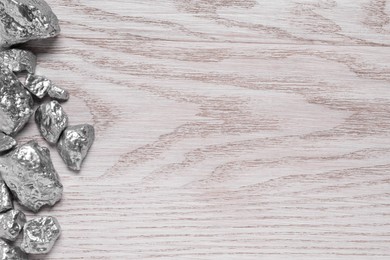 Pile of silver nuggets on white wooden table, flat lay. Space for text