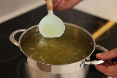 Man cooking delicious chicken soup in kitchen, closeup