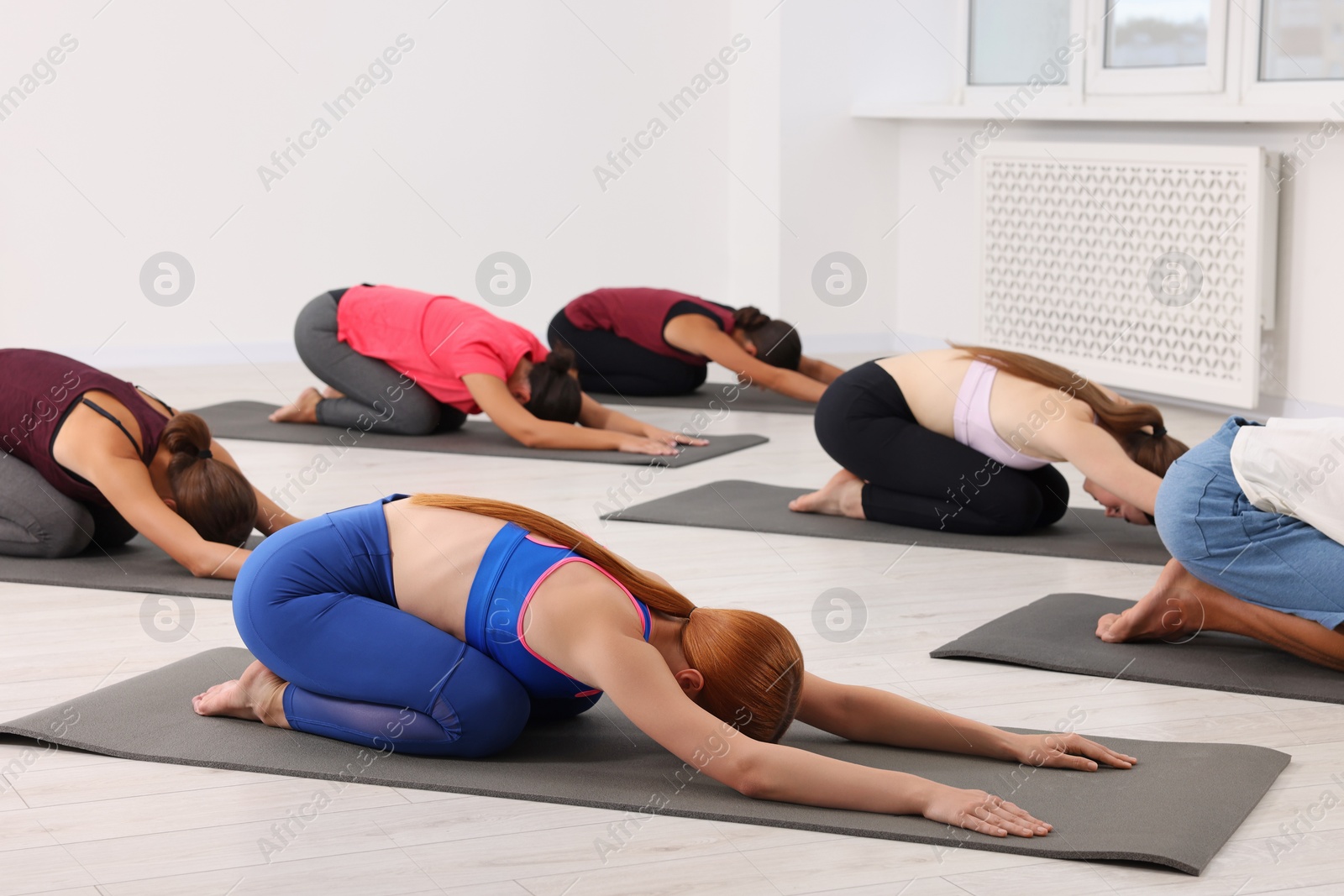 Photo of Group of people practicing yoga on mats indoors