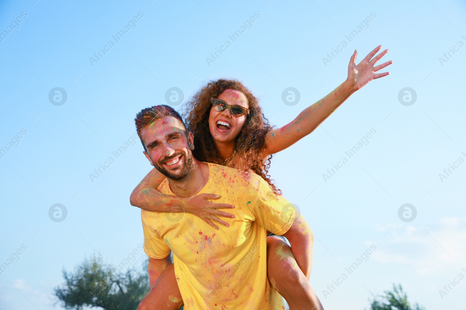 Photo of Happy couple covered with colorful powder dyes outdoors. Holi festival celebration