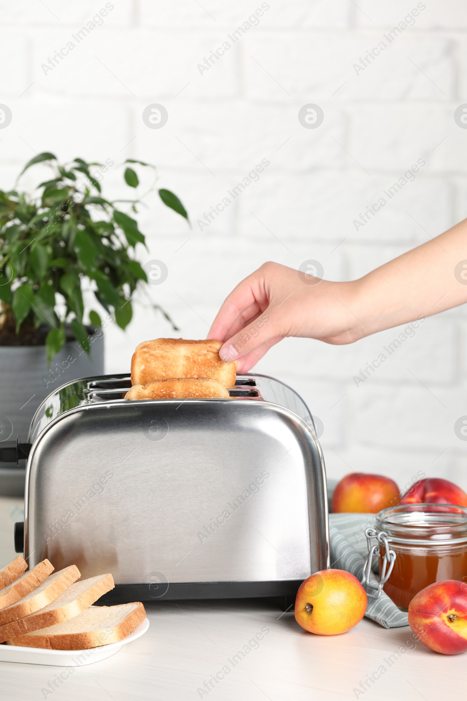 Photo of Woman taking off roasted bread from toaster, closeup