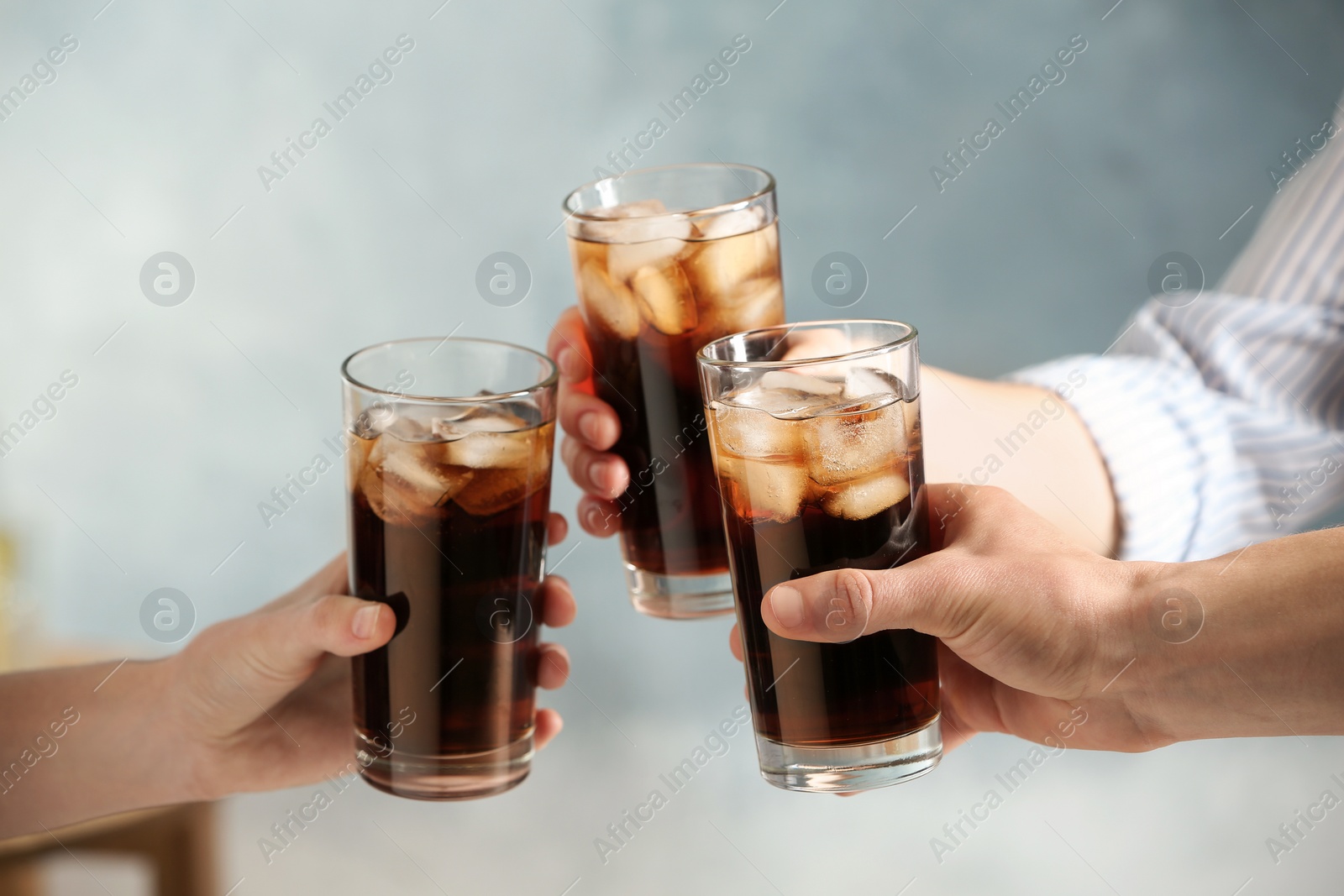 Photo of Friends with glasses of cold cola on color background, closeup