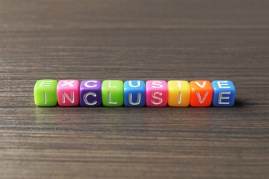 Photo of Colorful cubes with word Inclusive on wooden table