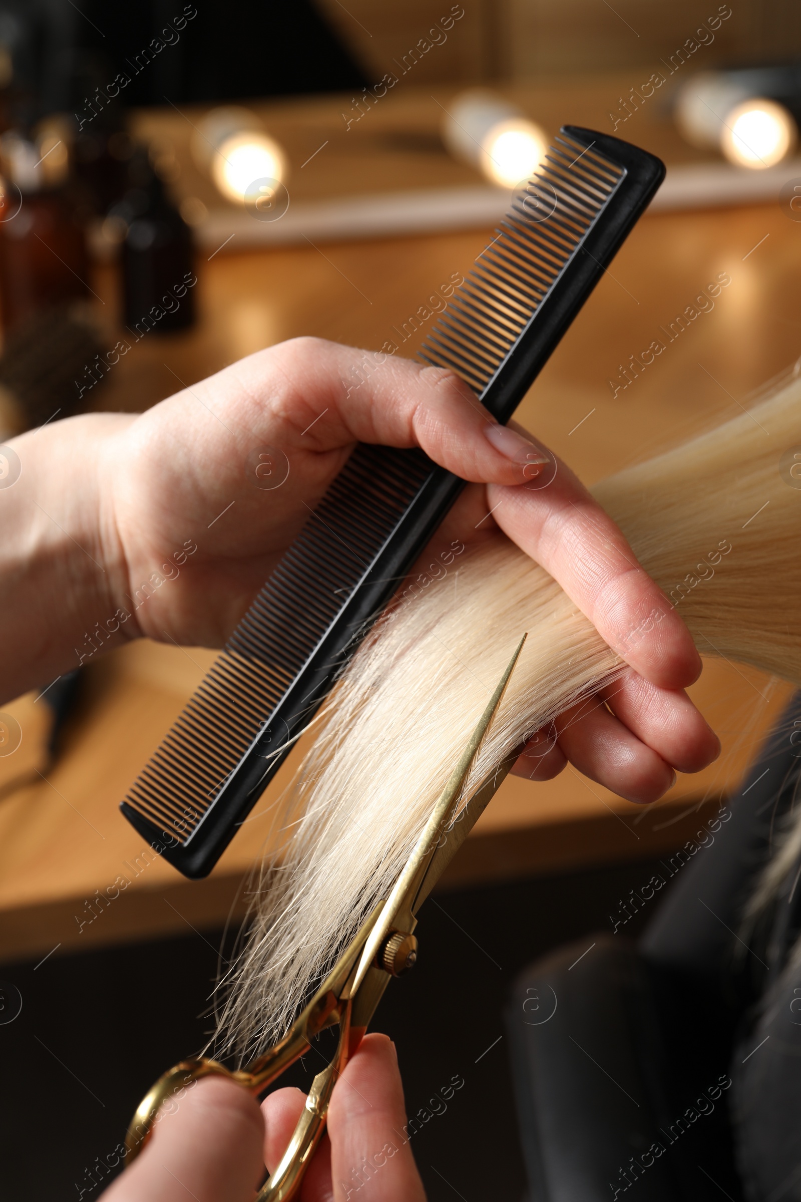 Photo of Hairdresser cutting client's hair with scissors in salon, closeup