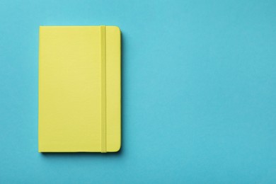 Photo of New stylish planner with hard cover on light blue background, top view. Space for text