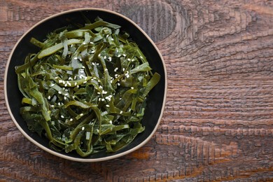 Photo of Fresh laminaria (kelp) seaweed in bowl on wooden table. Space for text