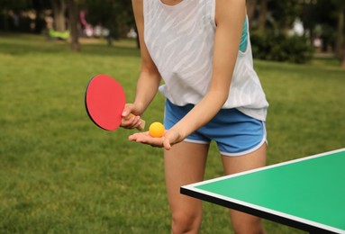 Photo of Woman playing ping pong outdoors on summer day, closeup