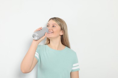 Photo of Beautiful woman drinking from beverage can on light background