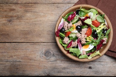 Photo of Bowl of delicious salad with canned tuna and vegetables on wooden table, flat lay. Space for text