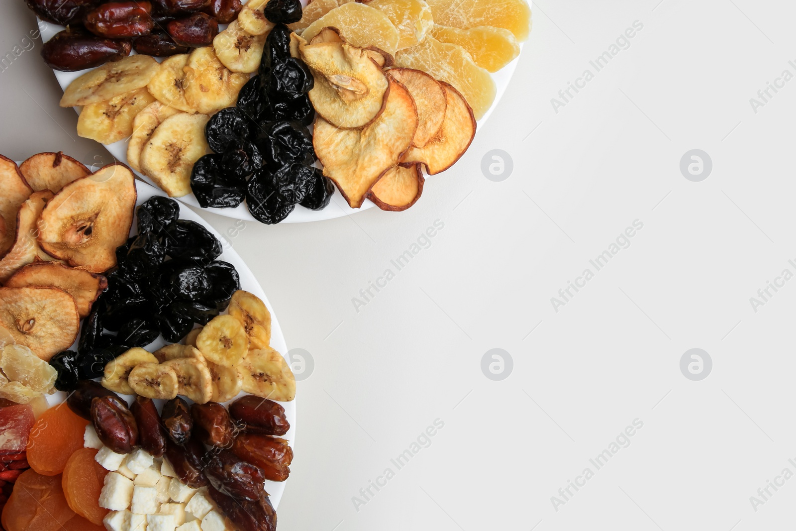 Photo of Plates with different dried fruits on white background, top view. Space for text