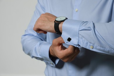 Photo of Stylish man putting on cufflink against grey background, closeup