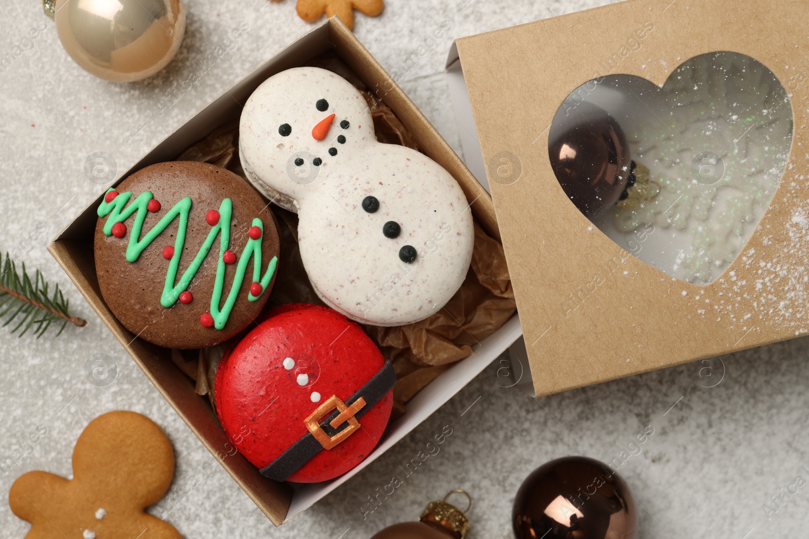 Photo of Tasty Christmas macarons in box and festive decor on table, flat lay