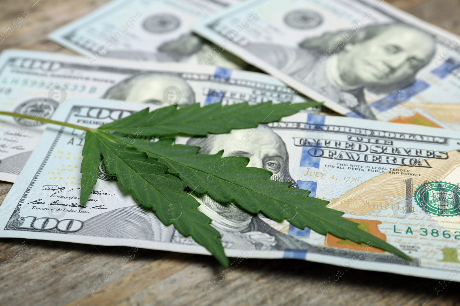 Photo of Hemp leaf and money on wooden table, closeup