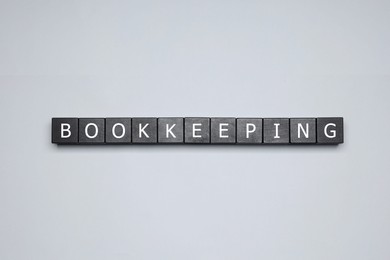 Photo of Word Bookkeeping made with black cubes on light grey background, top view