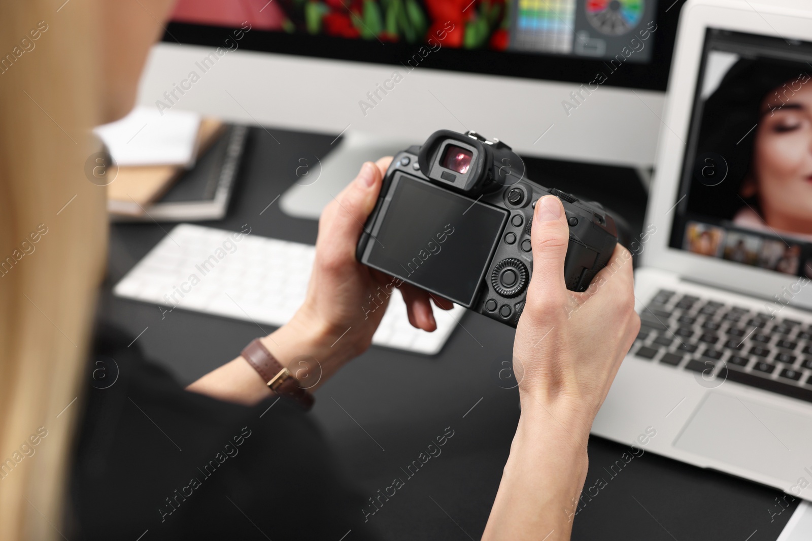 Photo of Professional photographer with digital camera at table indoors, closeup