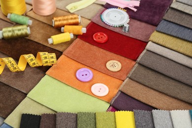 Photo of Different sewing accessories on colorful fabric samples