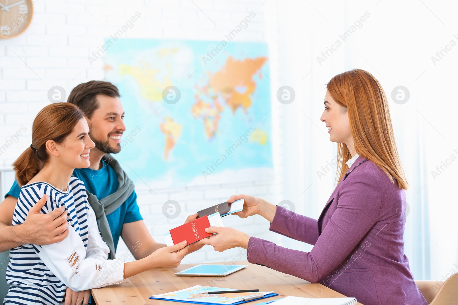 Photo of Female manager giving passports with tickets to couple in travel agency