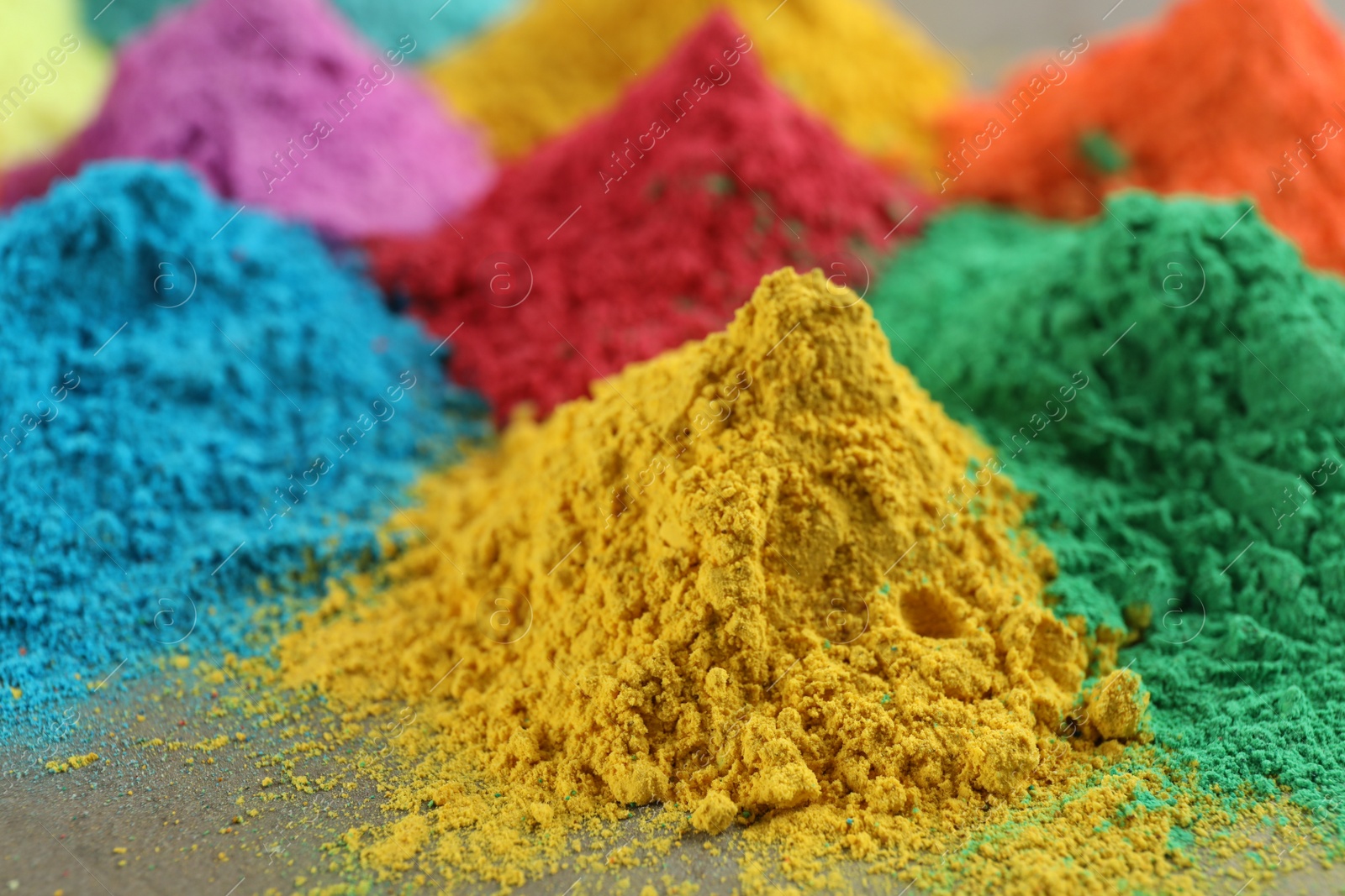 Photo of Colorful powder dyes on grey background, closeup. Holi festival