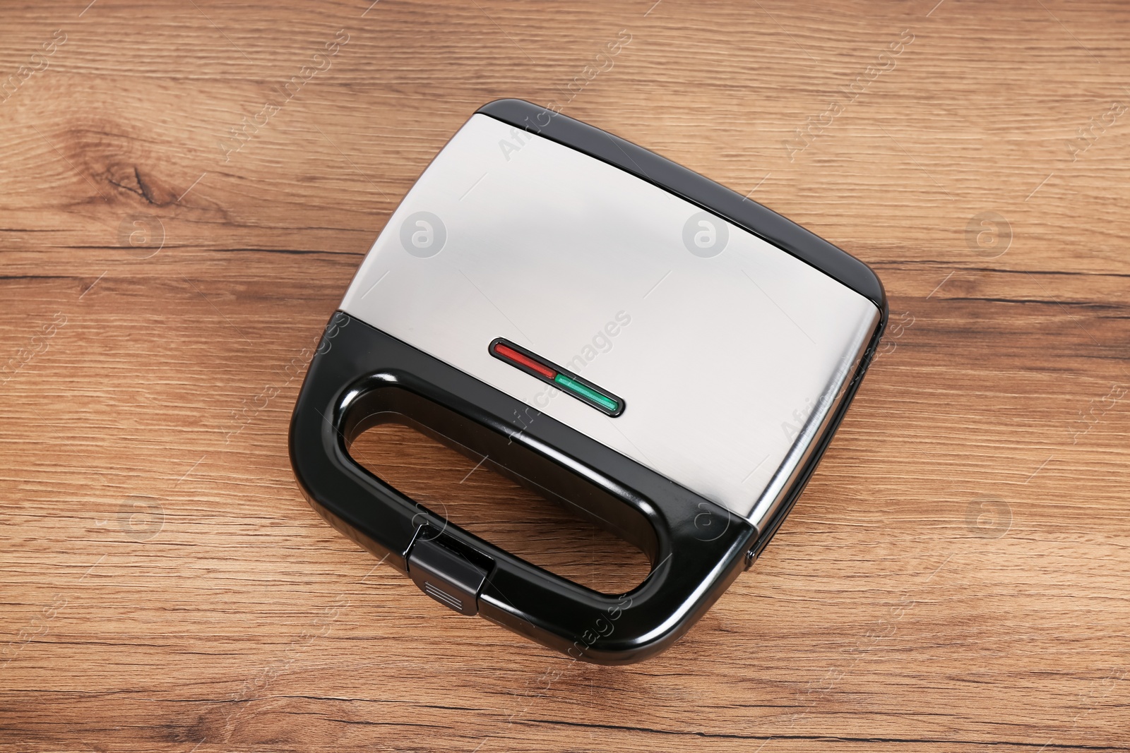 Photo of Modern electric sandwich maker on wooden table, above view