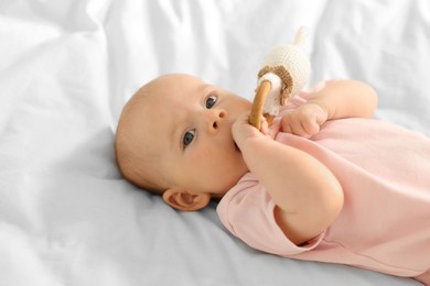 Photo of Cute little baby with toy on white sheets