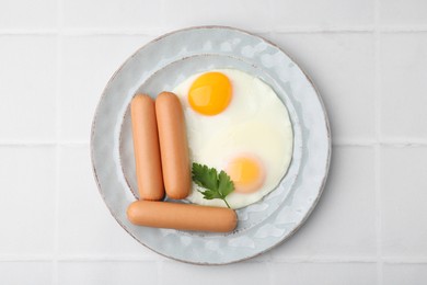 Photo of Delicious boiled sausages, fried eggs and parsley on white tiled table, top view
