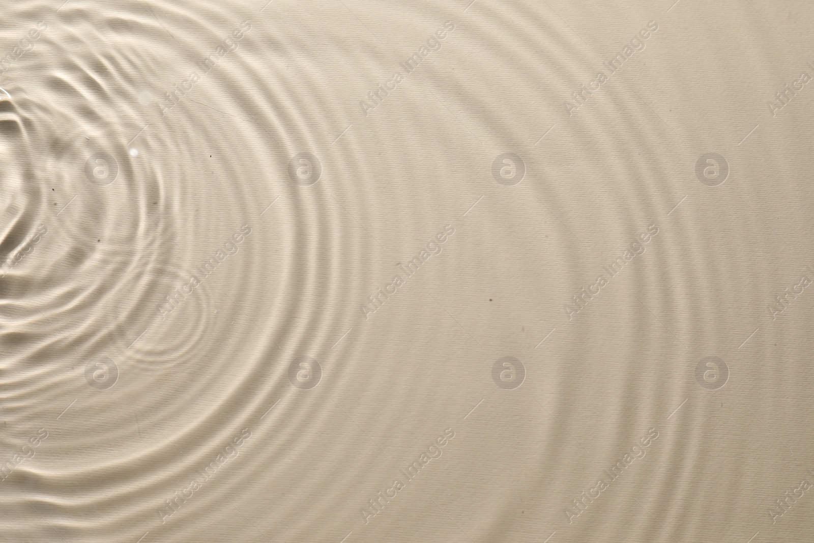 Photo of Rippled surface of clear water on beige background, top view