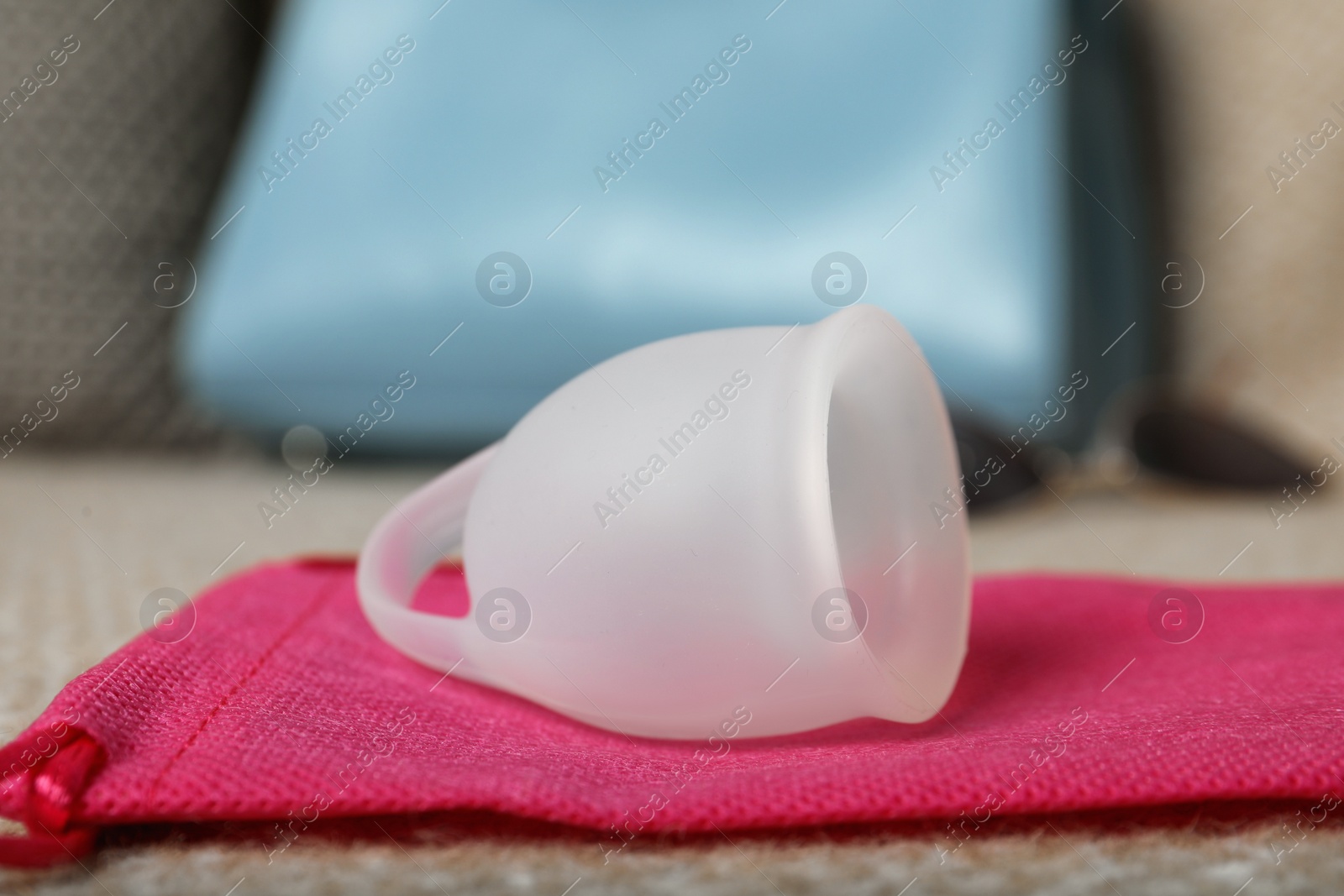 Photo of White menstrual cup with bag on sofa, closeup