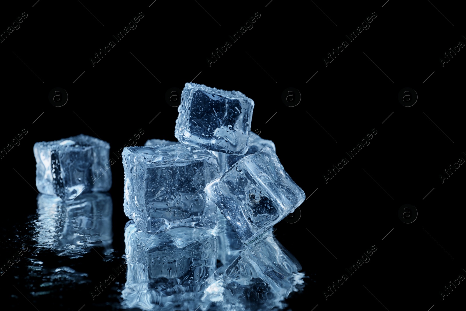 Photo of Ice cubes on black mirror surface. Space for text