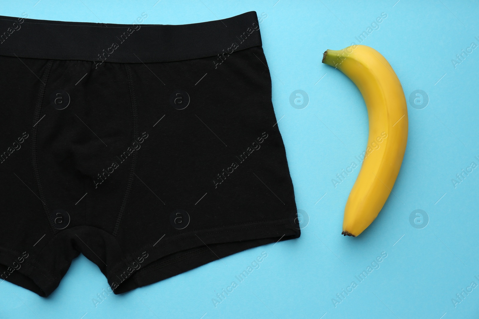 Photo of Men's underwear and banana on light blue background, flat lay. Potency problem concept
