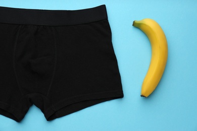Photo of Men's underwear and banana on light blue background, flat lay. Potency problem concept