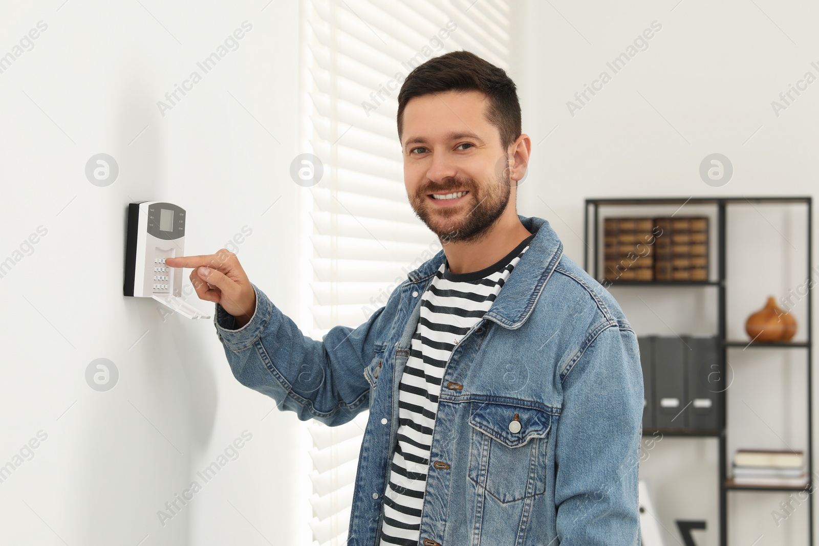 Photo of Man entering code on home security system indoors