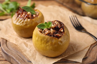 Photo of Baked apples and parchment on wooden board, closeup