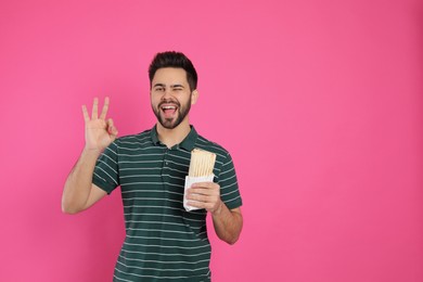 Photo of Happy young man with tasty shawarma showing okay gesture on pink background. Space for text