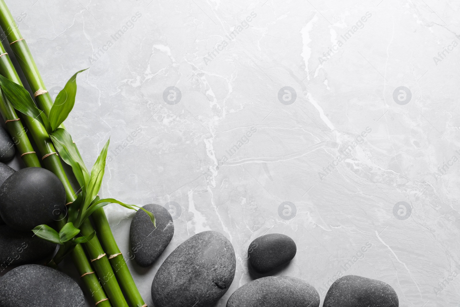 Photo of Spa stones and bamboo stems on light grey table, flat lay. Space for text