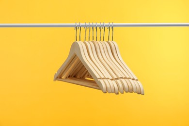 Photo of Empty clothes hangers on rack against orange background