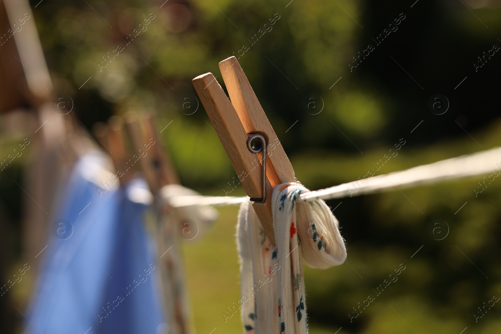 Photo of Clean clothes drying in garden, closeup. Focus on clothespin