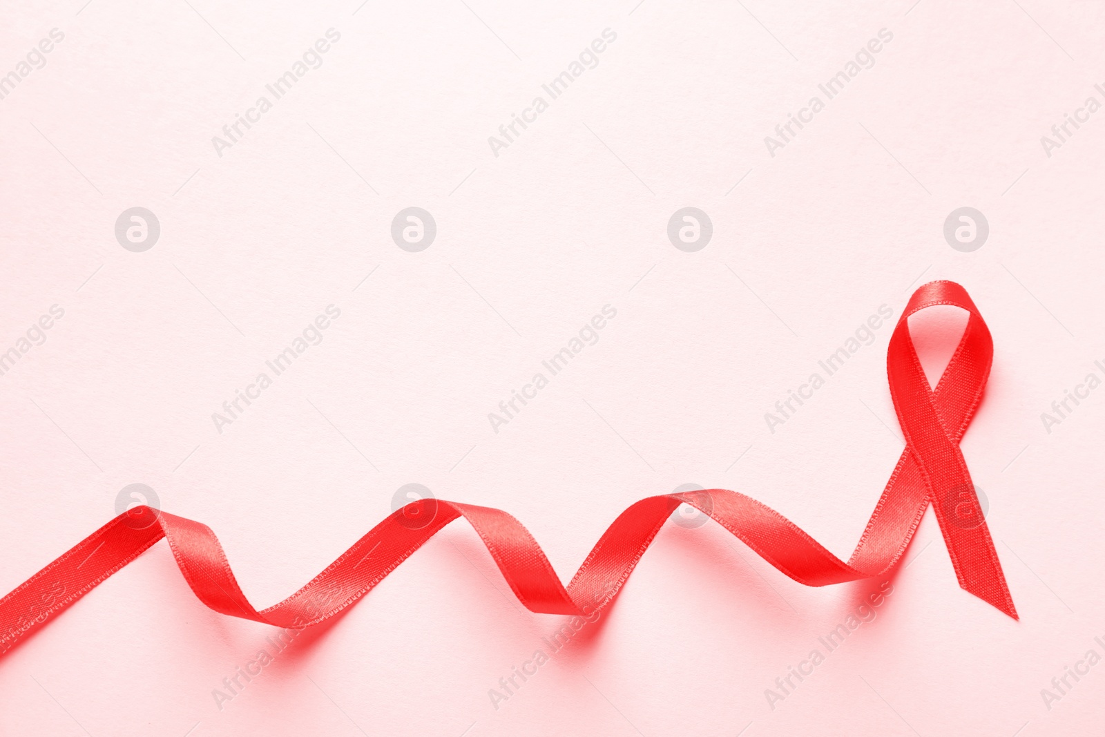 Photo of Red ribbon on color background, top view. Cancer awareness