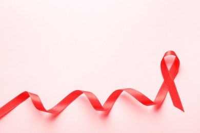 Photo of Red ribbon on color background, top view. Cancer awareness
