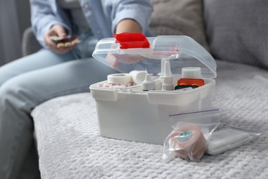 Photo of Woman holding pills indoors, focus on first aid kit